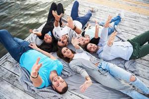 grupo de jóvenes felices y hermosos que están haciendo aldea en el muelle, los mejores amigos de niñas y niños con la noción de placer crean vidas emocionales foto