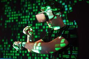 Double exposure of a caucasian man and Virtual reality headset is presumably a gamer or a hacker cracking the code into a secure network or server, with lines of code photo
