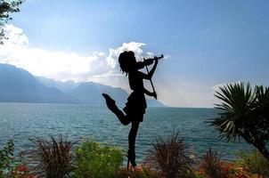 Montreux, Switzerland - September 14, 2017 Figure silhouette of girl with violin on promenade of the Lake Leman Lake Geneva in front of mountains Alps, Swiss Riviera, Vaud canton photo