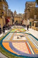 victoria, malta - 12 de marzo de 2017 coloridas flores de mosaico dibujando alfombra en la calle cerca del antiguo castillo medieval de la torre cittadella, también conocido como ciudadela, castello en la ciudad de victoria rabat, isla de gozo foto