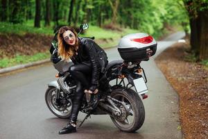 An attractive sexy girl on a sports motorbike posing outside photo