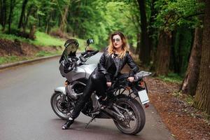 An attractive sexy girl on a sports motorbike posing outside photo