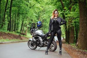 An attractive sexy girl on a sports motorbike posing outside photo