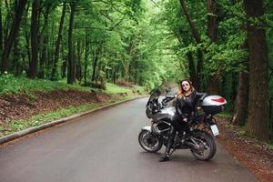 An attractive sexy girl on a sports motorbike posing outside photo