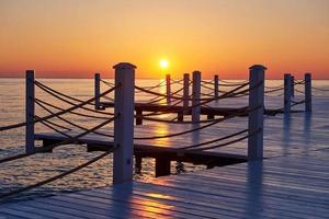 Wooden pier on a fancy orange sunset. photo