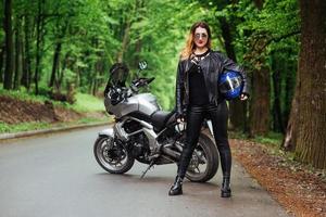 An attractive sexy girl on a sports motorbike posing outside photo