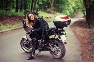 An attractive sexy girl on a sports motorbike posing outside photo