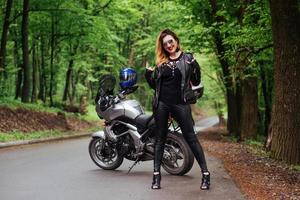 An attractive sexy girl on a sports motorbike posing outside photo