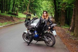 An attractive sexy girl on a sports motorbike posing outside photo