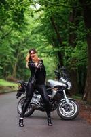 An attractive sexy girl on a sports motorbike posing outside photo