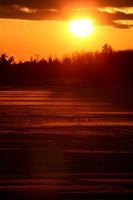 puesta de sol detrás de un lago saskatchewan congelado foto