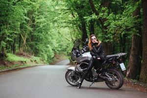 una atractiva chica sexy en una moto deportiva posando afuera foto