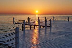 Wooden pier on a fancy orange sunset. photo