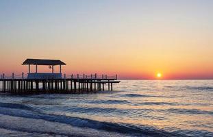 muelle de madera en una elegante puesta de sol naranja. foto