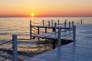 muelle de madera en una elegante puesta de sol naranja. foto