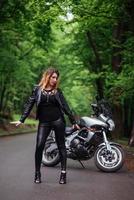 An attractive sexy girl on a sports motorbike posing outside photo