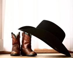 sombrero de vaquero apoyado en botas pequeñas foto