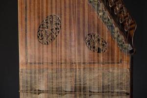 ancient Asian stringed musical instrument on black background with backlight. the similarity of the harp and psaltery. closeup photo