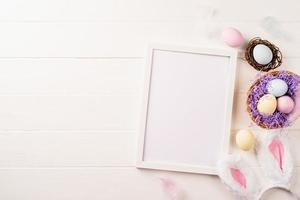 White frame with easter decorations flat lay on beige background photo