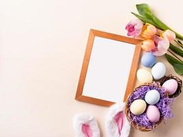 Wooden frame with easter decorations flat lay on beige background photo