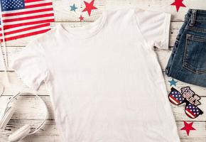 Mockup design white t shirt for logo, top view on white wooden background with US flag, shoes and jeans photo