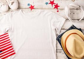 Mockup design white t shirt for logo, top view on white wooden background with US flag and decoration photo