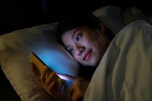 Young Asian woman using smartphone at midnight photo