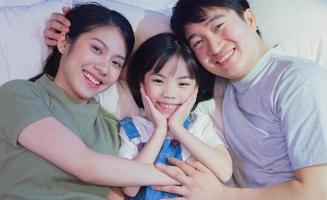 joven familia asiática en la cama foto