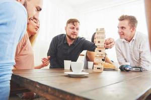 grupo de amigos creativos sentados en la mesa de madera. gente divirtiéndose mientras juega al juego de mesa. foto