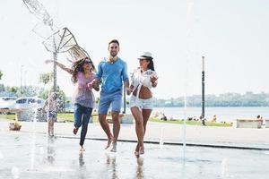 grupo de amigos divirtiéndose junto a la fuente pública el día de verano foto