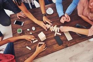 Top view creative photo of friends sitting at wooden table. Friends having fun while playing board game