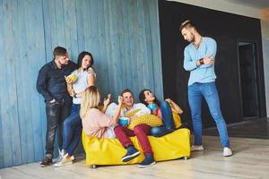 retrato grupal de niños y niñas multiétnicos con ropa colorida de moda sosteniendo a un amigo y posando en una pared de ladrillo, gente de estilo urbano divirtiéndose, conceptos sobre la juventud y el estilo de vida foto