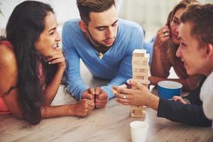 grupo de amigos creativos sentados en la mesa de madera. gente divirtiéndose mientras juega al juego de mesa. foto