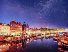 Beautiful night in Amsterdam. Night illumination of buildings and boats near the water in the canal. photo