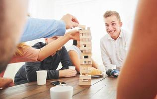 grupo de amigos creativos sentados en la mesa de madera. gente divirtiéndose mientras juega al juego de mesa. foto