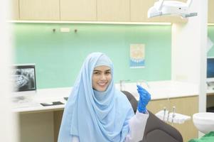 joven dentista musulmana sosteniendo invisalign en clínica dental, chequeo de dientes y concepto de dientes sanos foto