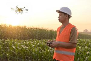 ingeniero masculino que controla la fumigación de fertilizantes y pesticidas con drones sobre tierras de cultivo, innovaciones de alta tecnología y agricultura inteligente foto