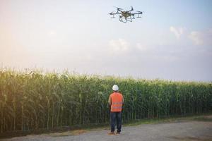 ingeniero masculino que controla la fumigación de fertilizantes y pesticidas con drones sobre tierras de cultivo, innovaciones de alta tecnología y agricultura inteligente foto