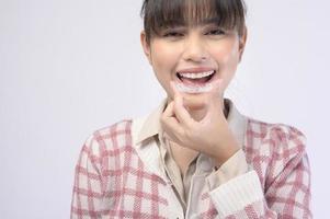 Young smiling woman holding invisalign braces over white background studio, dental healthcare and Orthodontic concept. photo