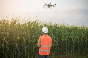 ingeniero masculino que controla la fumigación de fertilizantes y pesticidas con drones sobre tierras de cultivo, innovaciones de alta tecnología y agricultura inteligente foto