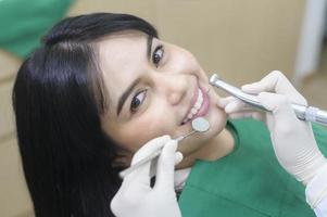 una mujer joven con dientes examinados por un dentista en una clínica dental, revisión de dientes y concepto de dientes sanos foto