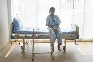 Senior man helping cancer patient woman wearing head scarf with walker at hospital, health care and medical concept photo