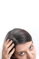 Young woman with graying hair on a white background. The concept of early gray hair. Vertical photo