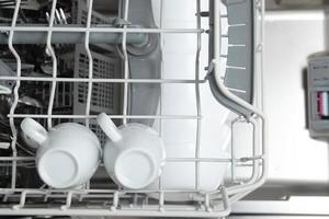 White dishes in the dishwasher. Homework with dishwasher concept