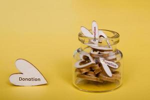 Wooden hearts next to and inside the bottle. Concept for alms, charity, fundraising, donation photo