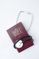 Holi bible with medical stethoscope flat lay. Soul healing, mental health and healing concept photo