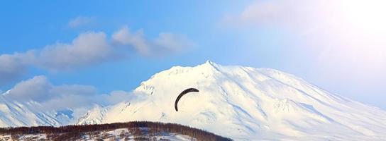 parapente volando contra el fondo del volcán en la península de kamchatka foto