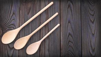 tres cucharas de madera sobre una mesa de madera oscura con espacio para copiar foto