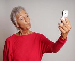 mature woman taking a smartphone selfie with duck face