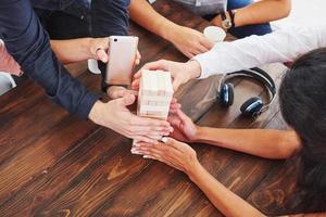 Top view creative photo of friends sitting at wooden table. Friends having fun while playing board game